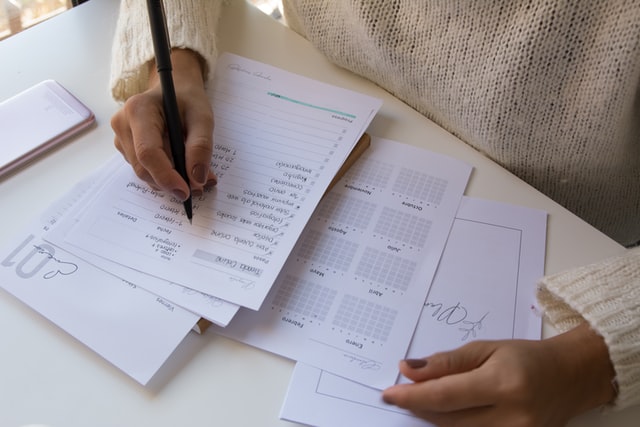 A person is managing a weekly to-do list on white paper.